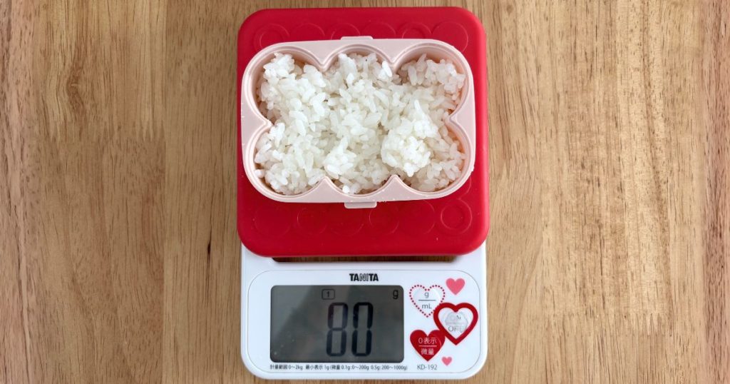 セリアの「ふるだけごはんメーカー」にご飯を詰めて、おにぎり1個あたりの重さを計量している写真