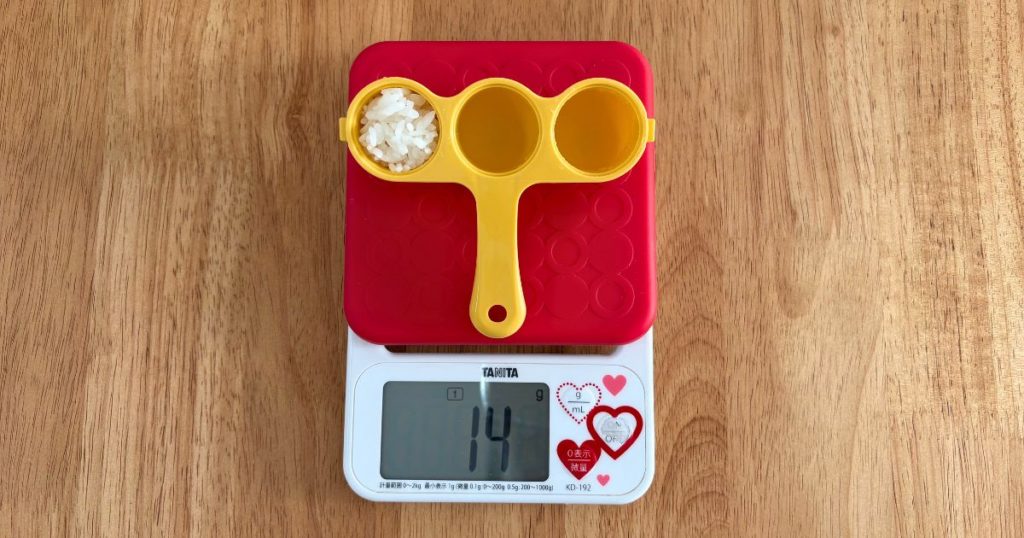 セリアの「ふりふりごはんボール」にご飯を詰めて、おにぎり1個あたりの重さを計量している写真
