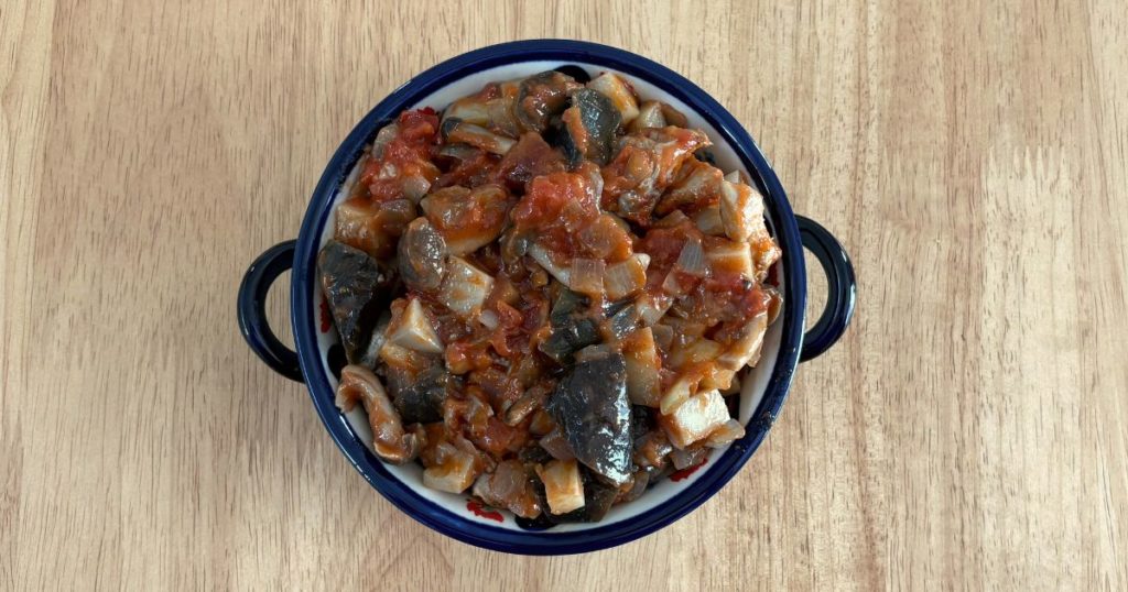 「鶏もも肉となすのトマト煮込み」をパン耳グラタン風にアレンジ。パン耳の上にトマト煮込みをのせた写真