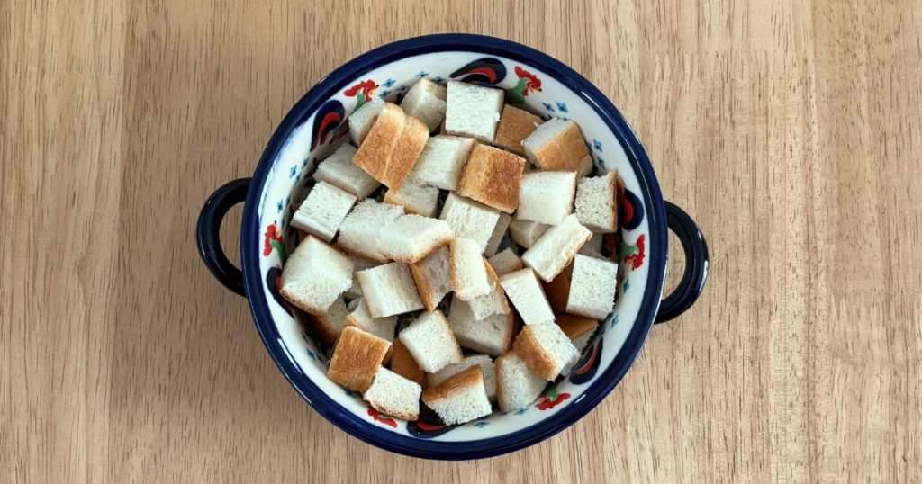 「鶏もも肉となすのトマト煮込み」をパン耳グラタン風にアレンジ。お皿にパン耳を敷き詰めた写真